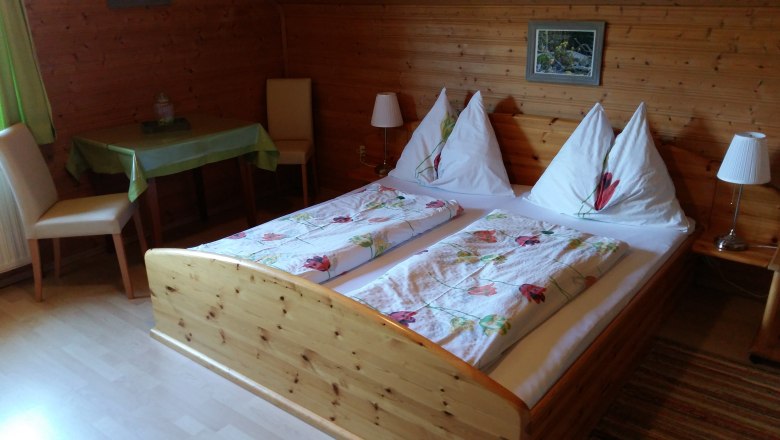 Rooms at the Wachabauer farm, © Wachabauer Cozy room with wooden walls, double bed and table at the Wachabauer farm.