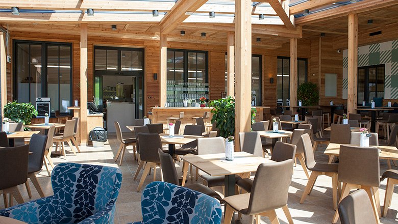 Eis-Greissler Kaffeehaus, © Blochberger Eisproduktion GmbH Ein modernes Kaffeehaus mit vielen Holzelementen, eckigen Tischen und braunen und blauen Stühlen.