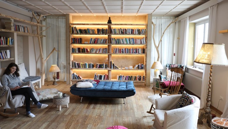 Library, © Kloster NaturSinne Cozy library with a large, illuminated bookshelf, armchairs and a person reading.