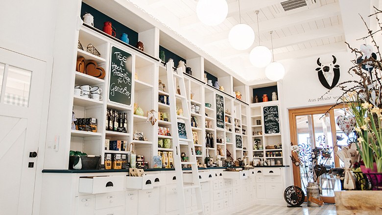 Eis-Greissler Hofladen innen, © Blochberger Eisproduktion GmbH Hofladen mit weißen Regalwänden gefüllt mit diversen Produkten, daneben Dekoration.