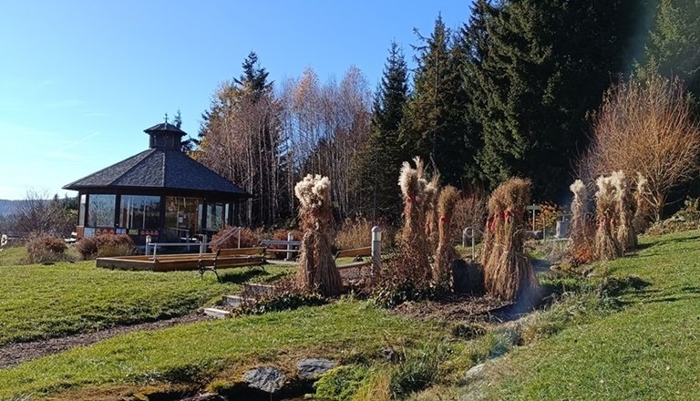 Herbststimmung in Mönichkirchen, © Glamping-Park Mönichkirchen OG Ein Pavillon in einer herbstlichen Landschaft mit Bäumen und einem kleinen Teich unter klarem Himmel.