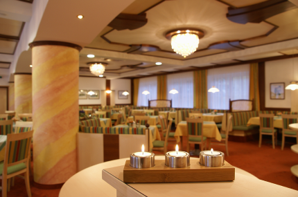 Hall in the Hotel Thier, © Franz Thier An elegant hotel room with laid tables, chandeliers and candles on a table in the foreground.