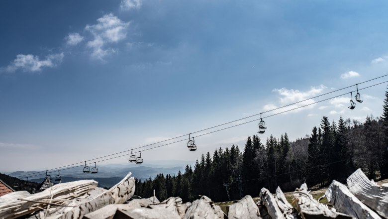 Alpengasthof Enzian, © Thomas Gobauer View of a cable car above a forest with a blue sky in the background.
