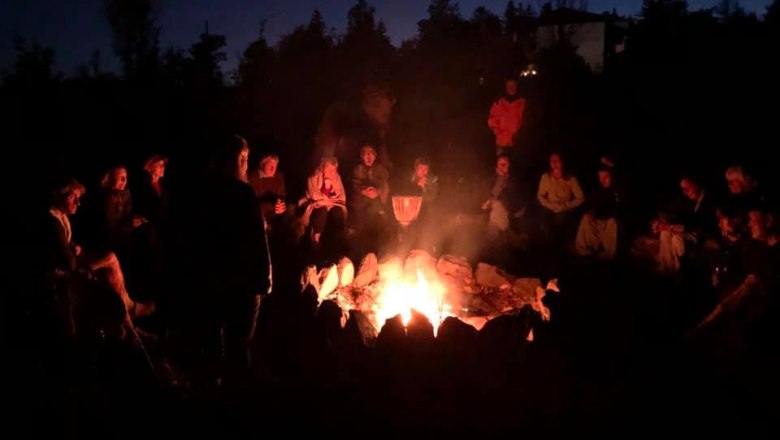 Full moon fire, © Kloster NaturSinne People sit in a circle around a campfire at night.