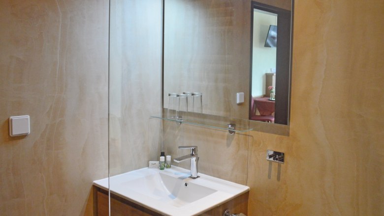 Badezimmer, © Gästehaus 3Länderblick / Anna Müllner Modernes Badezimmer mit Waschbecken, Spiegel und Glasregal.