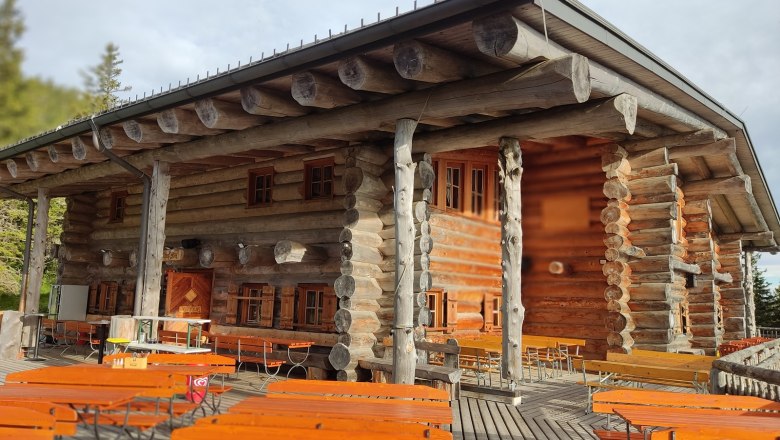 Terrasse, © Kulinarik zur Stoaalm/Steffen Holzhütte mit Terrasse und Bänken im Freien.
