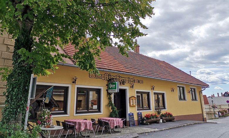Außenansicht eines traditionellen Gasthauses mit gelber Fassade und roten Dachziegeln.