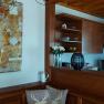 Wooden kitchen with artwork on the wall, vase with white roses and shelves with crockery.