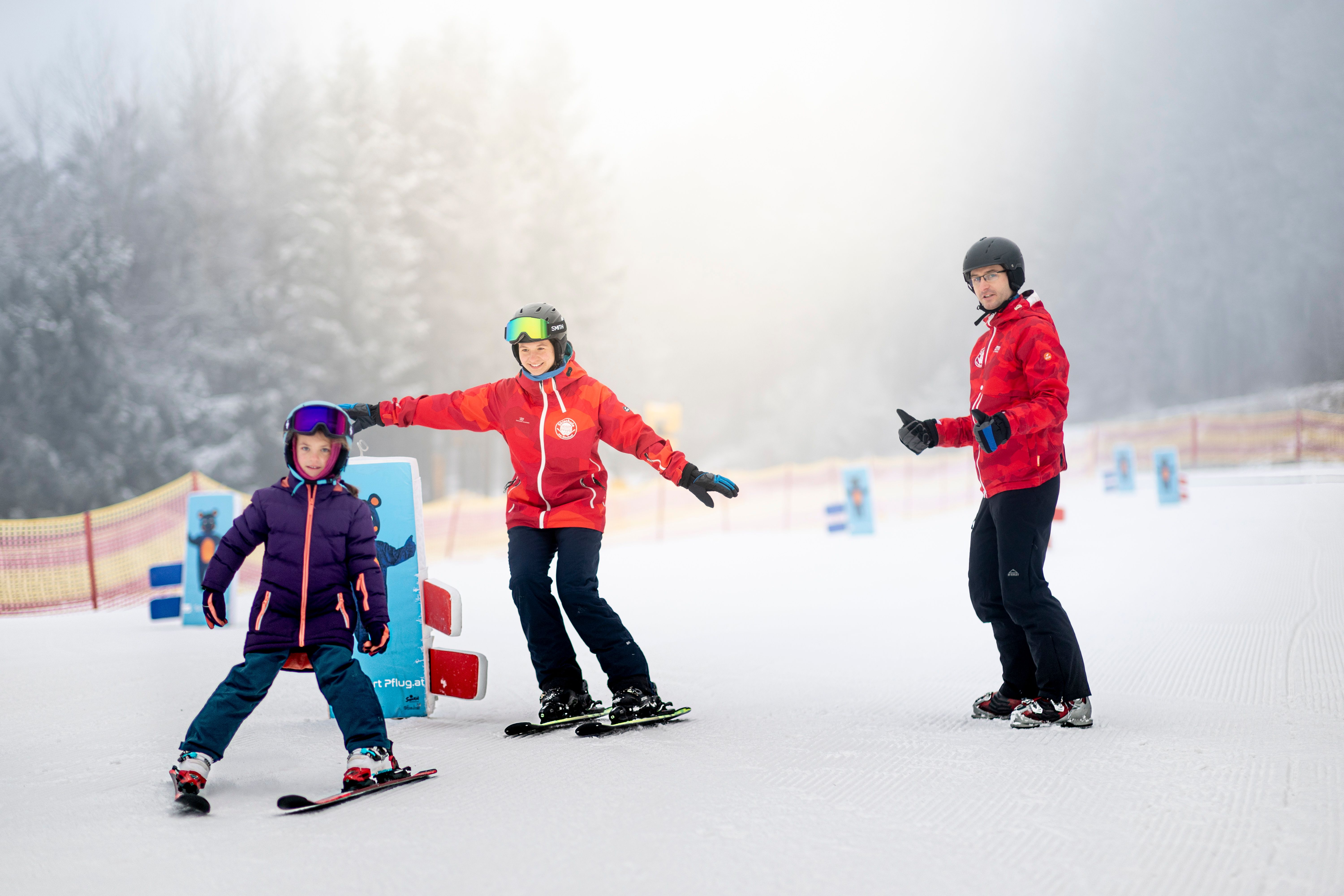 Kind fährt mit Skilehrerin im Kinderland einen Slalom.