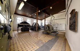 Innenansicht eines historischen Kraftwerks mit Maschinen und Ger&auml;ten.