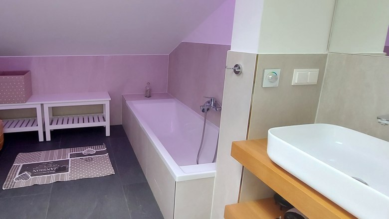 Modern bathroom with bathtub, washbasin and storage space.
