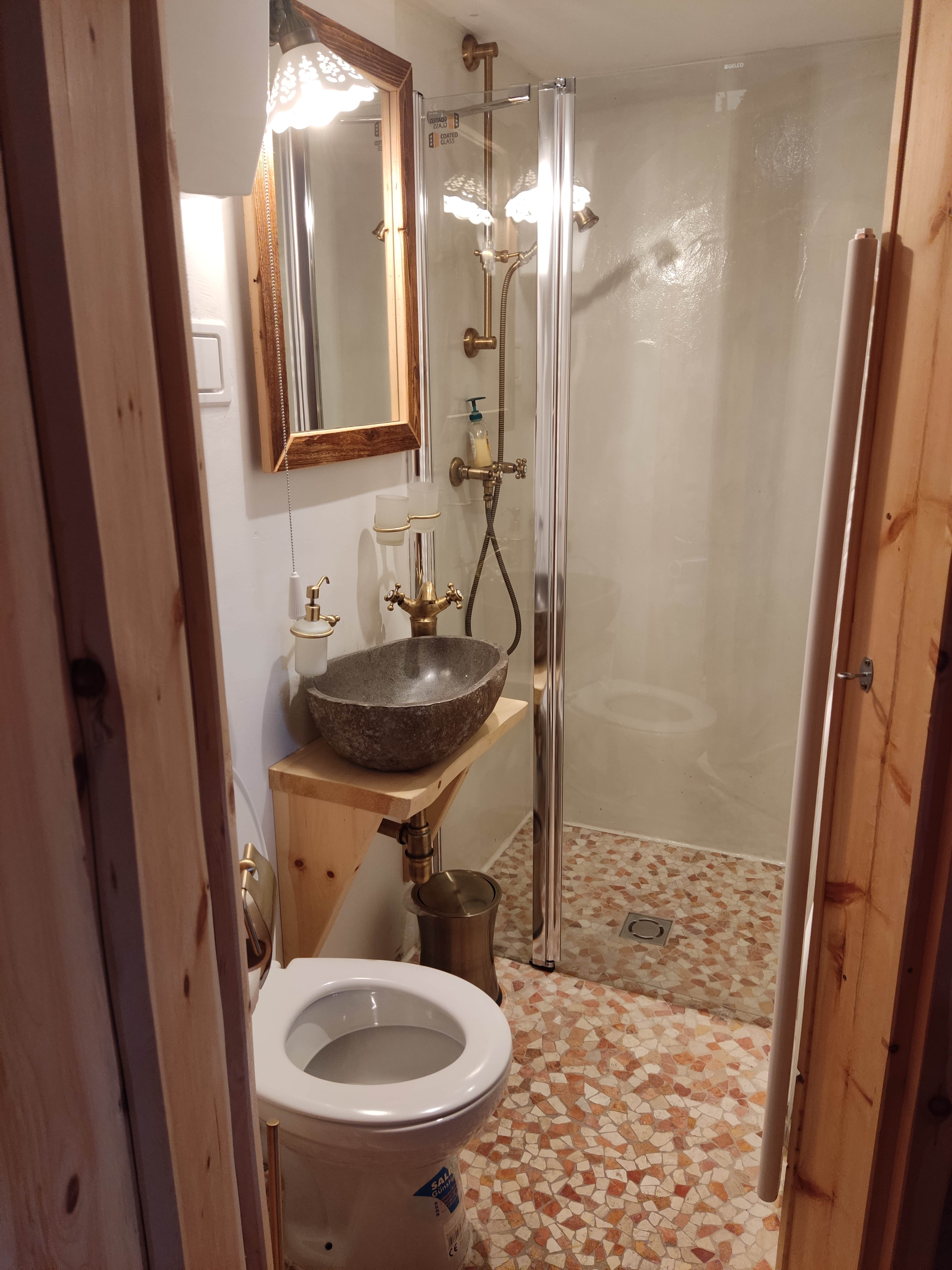 Kleines Badezimmer mit Dusche, Waschbecken und Toilette.