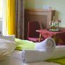Doppelzimmer mit Bett, Tisch, St&uuml;hlen und Balkon.