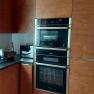Modern kitchen with wooden cupboards, built-in oven and worktop with kitchen appliances.