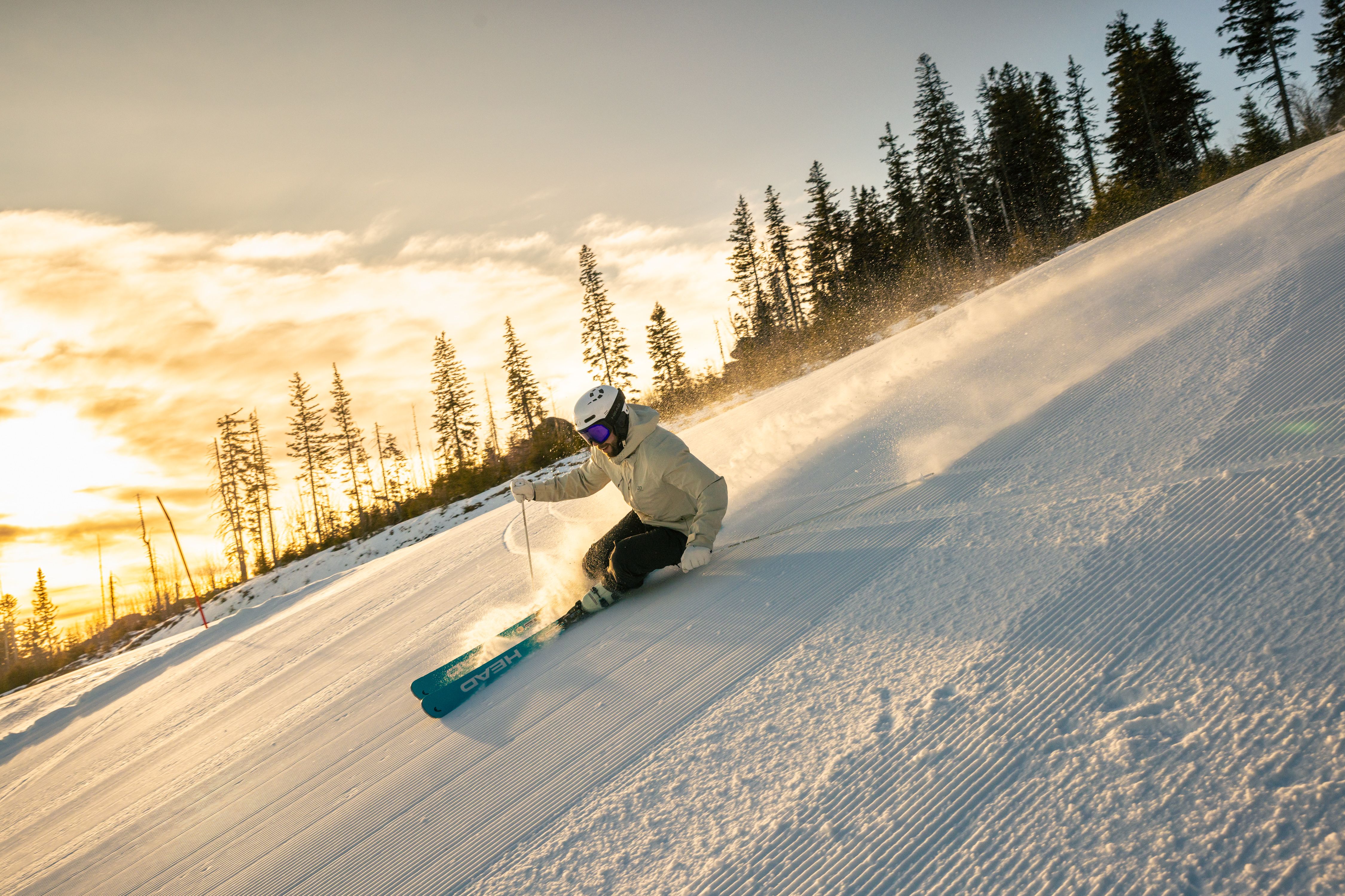 Skifahrer fährt sportlich die Piste hinunter bei morgendlicher Stimmung.