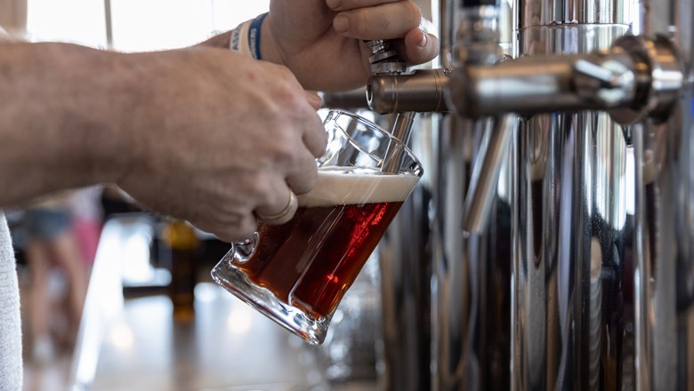 Person zapft Bier aus einem Zapfhahn in ein Glas.