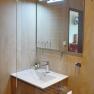 Modernes Badezimmer mit Waschbecken, Spiegel und Glasregal.
