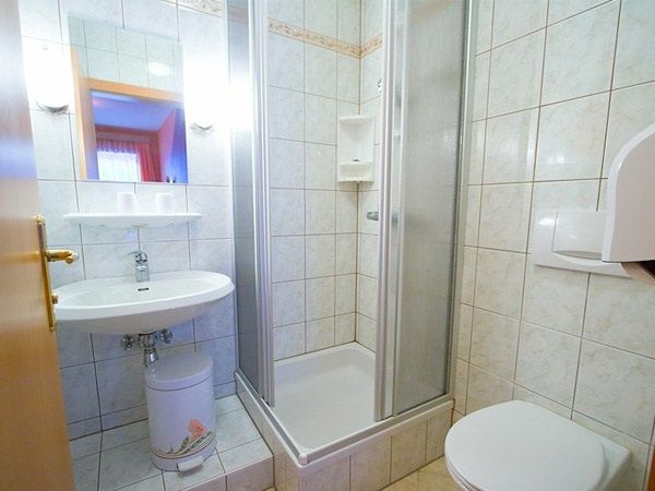 Kleines Badezimmer mit Dusche, Waschbecken und Toilette.