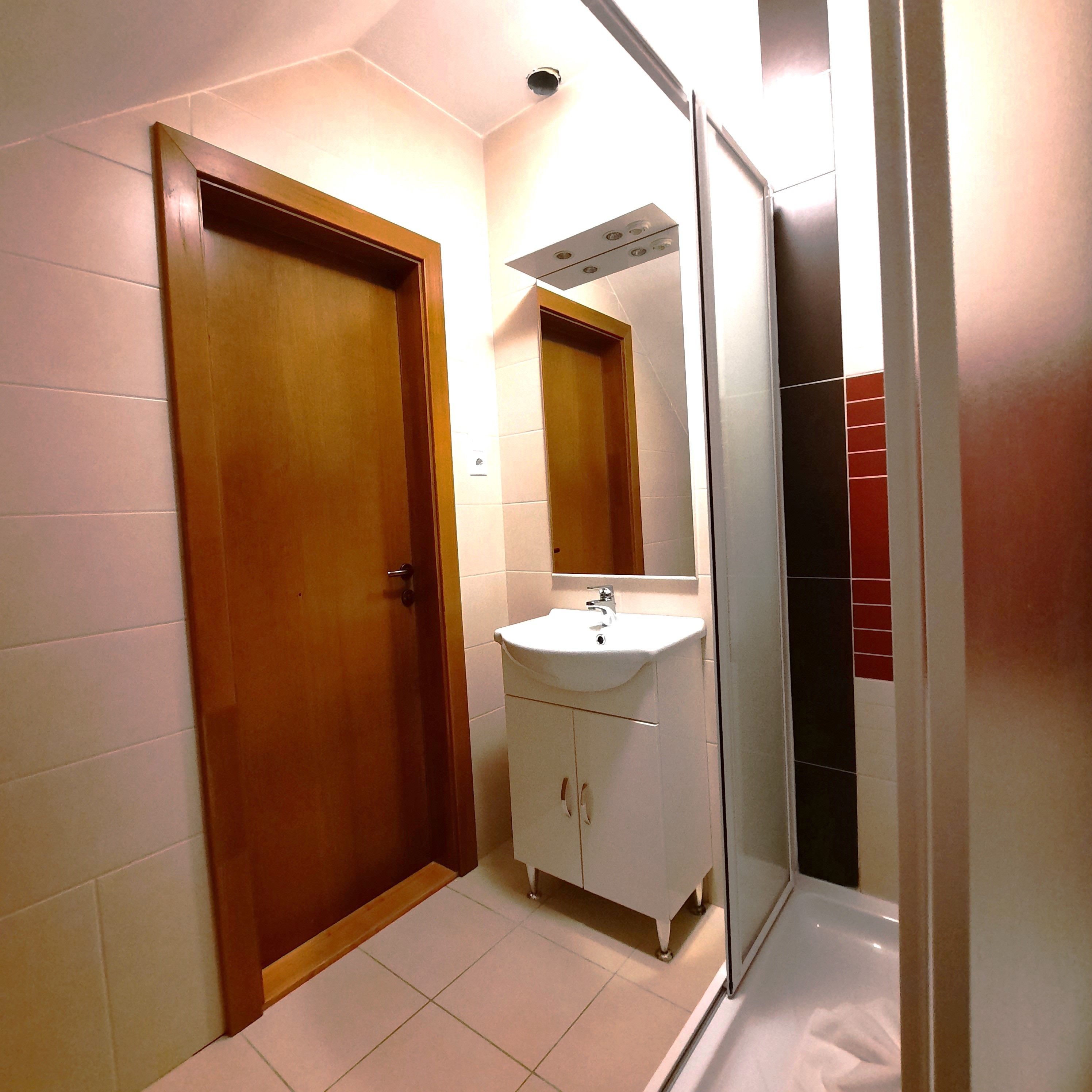Modernes Badezimmer mit Holztür, Waschbecken und Dusche.