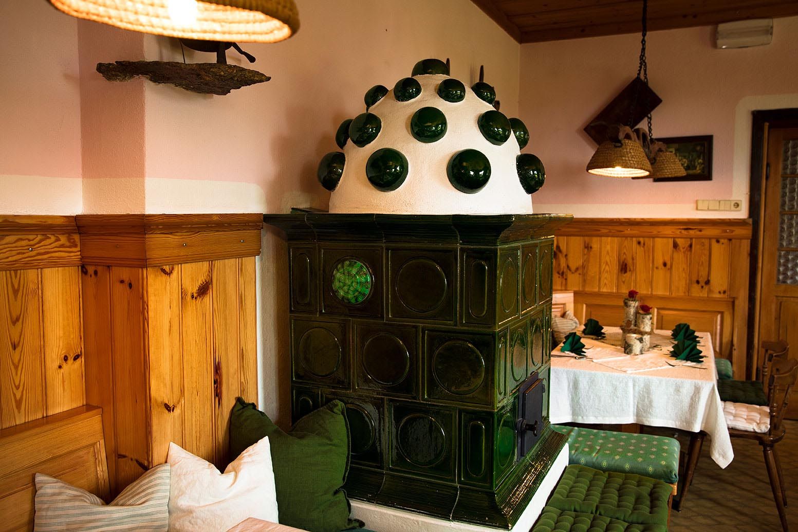 Gemütliche, traditionelle Gaststube mit grünem Kachelofen und Holzmöbeln.