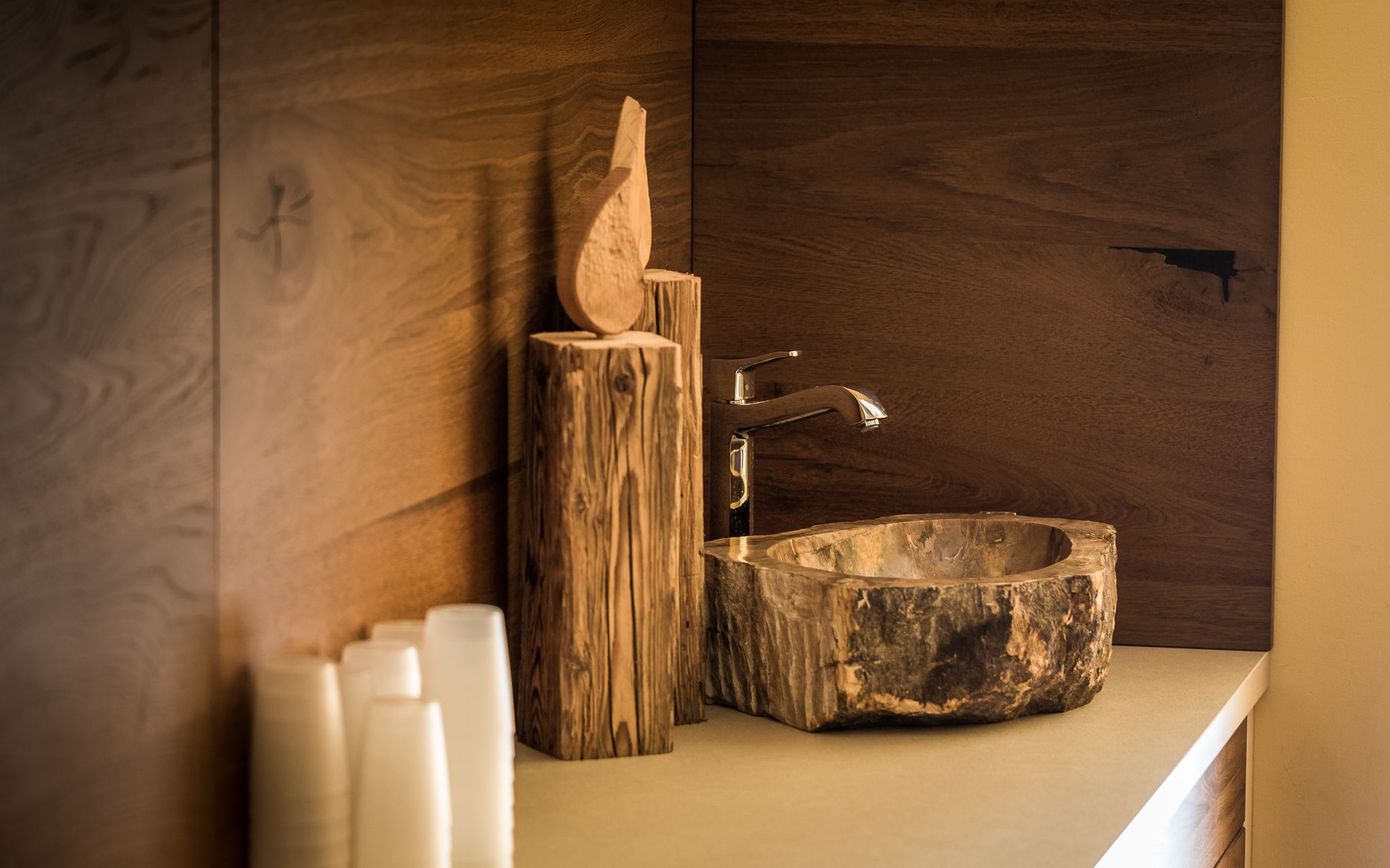 Rustikales Waschbecken aus Holz mit Wasserhahn und Holzdekor.