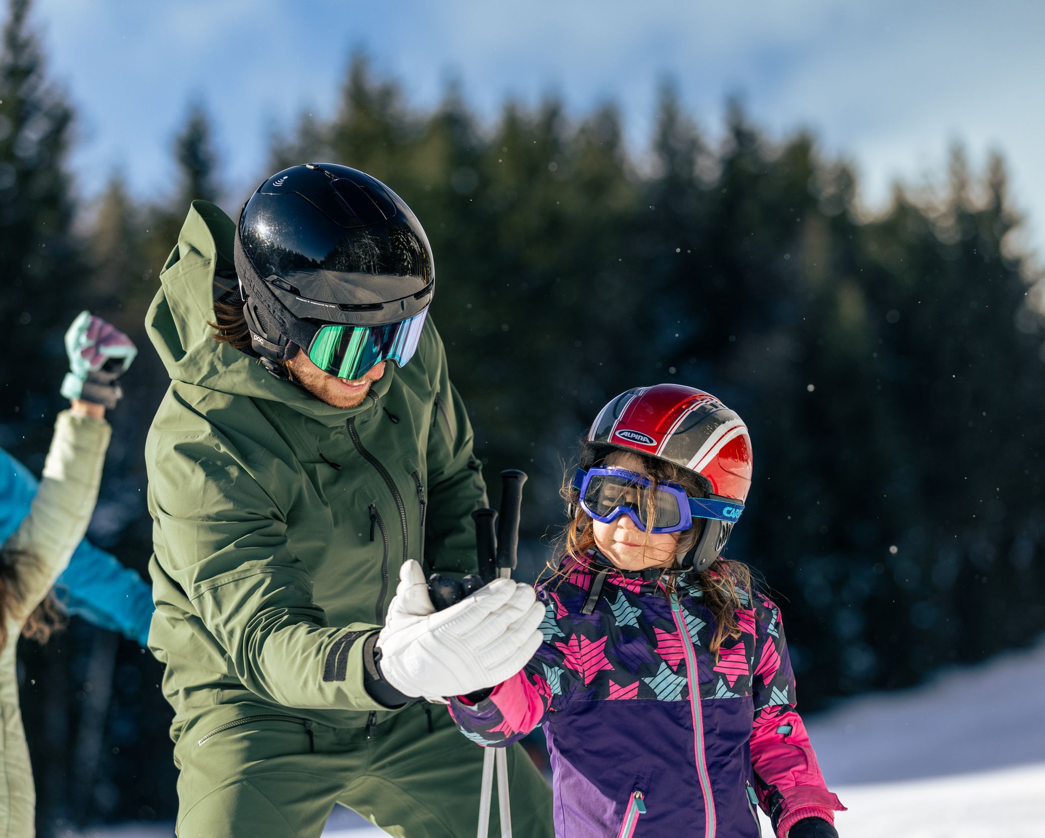 Tochter macht mit Vater High-Five beim Skifahren.