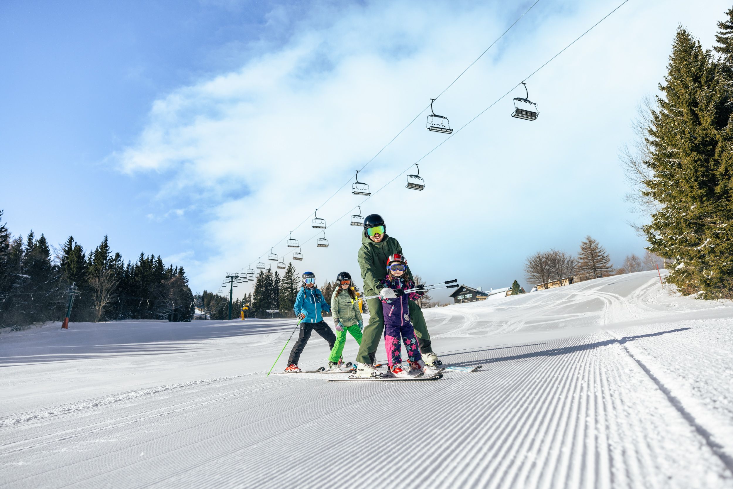 Eine Familie fährt auf der Erlebnisalm bei herrlichstem Wetter Ski.