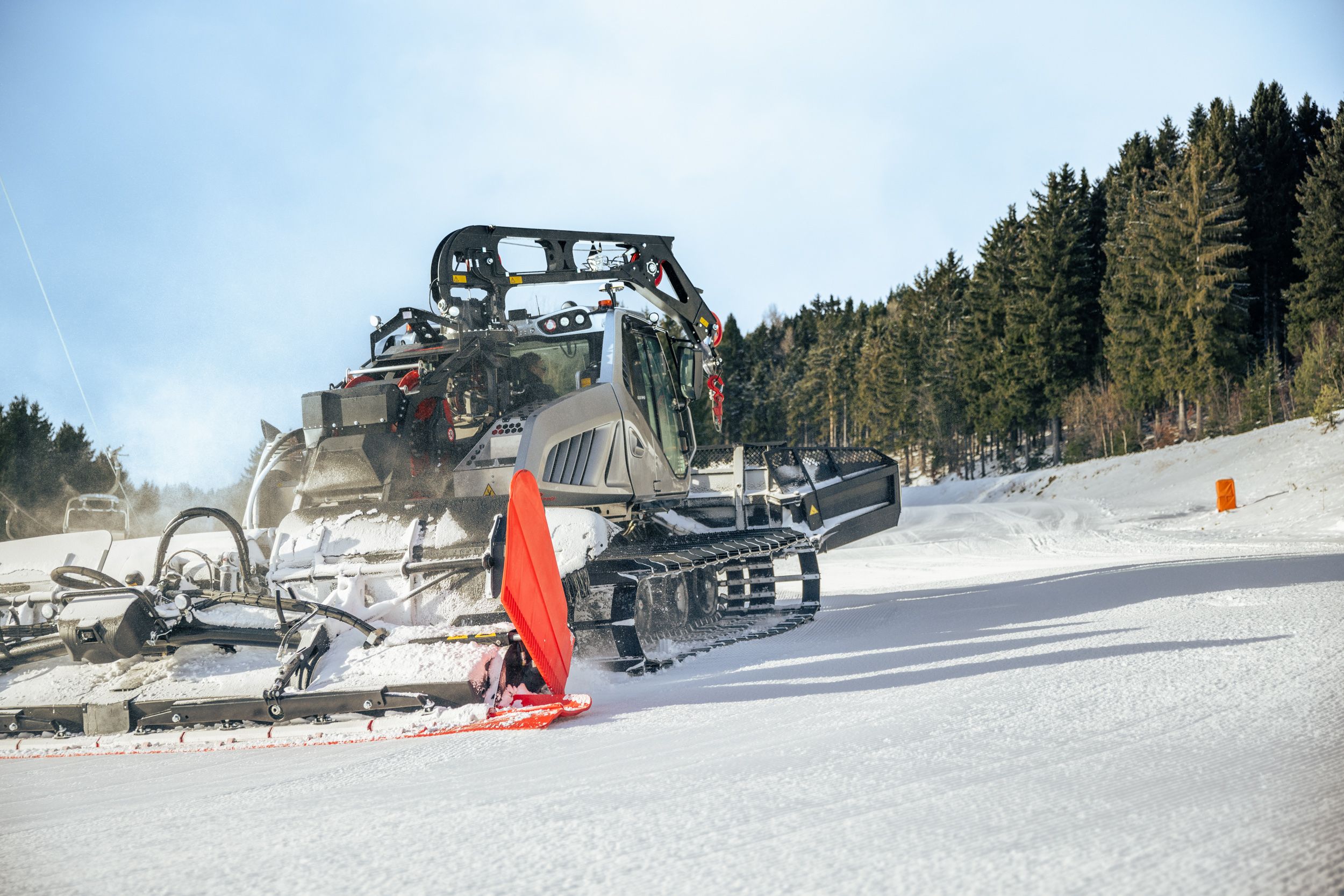 Ein Pistengerät präpariert die Skipiste und zieht dabei gleichmäßige Spuren in den Schnee.