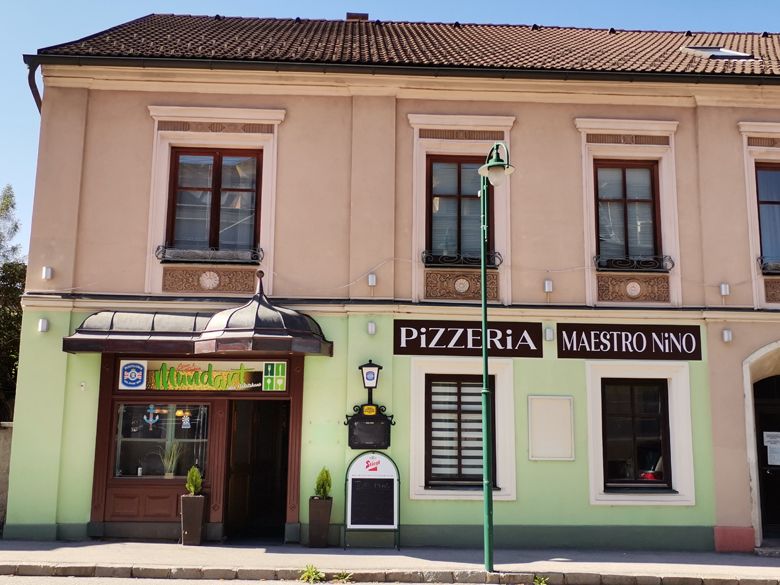 Fassade einer Pizzeria mit dem Namen Maestro Nino in einem zweistöckigen Gebäude.