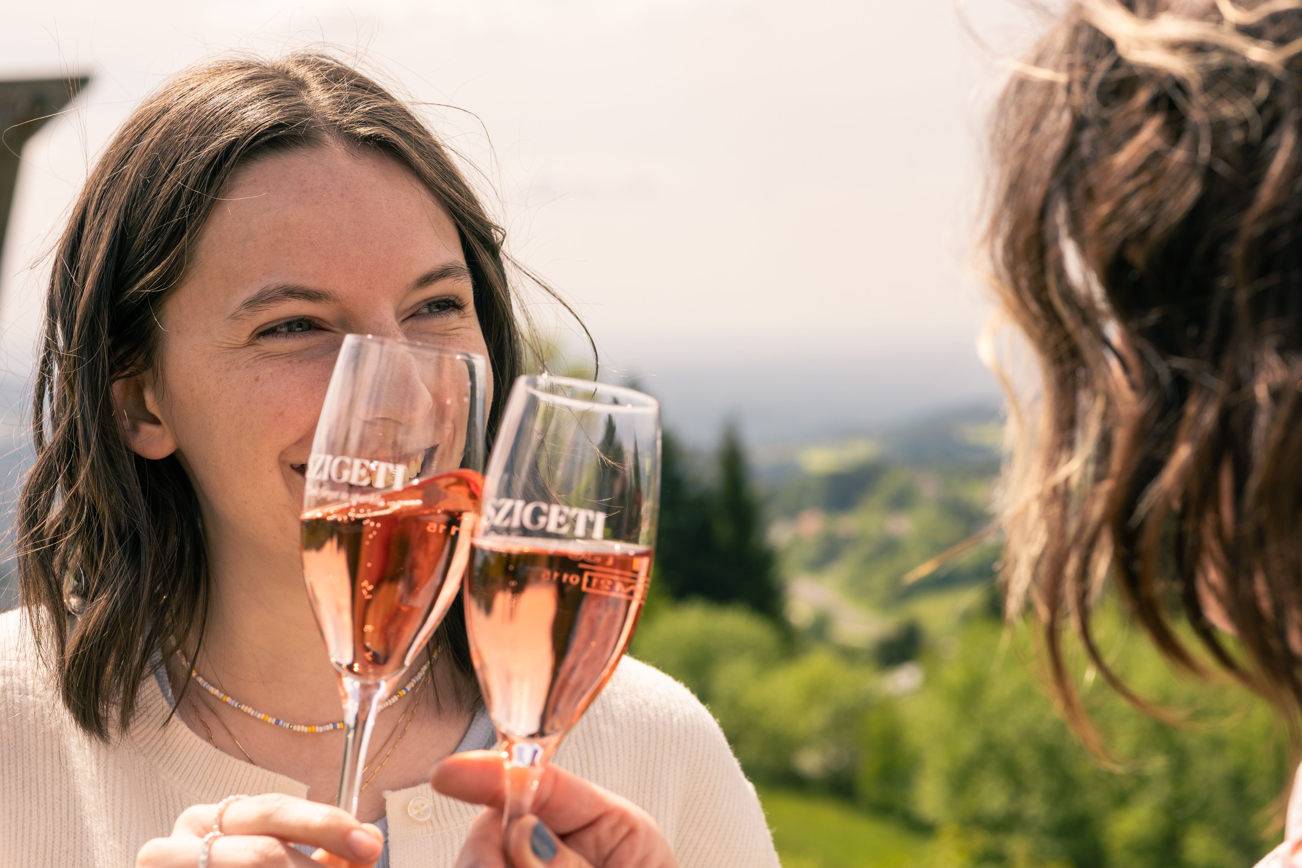 Zwei Freundinnen stoßen mit einem Glas Sekt an