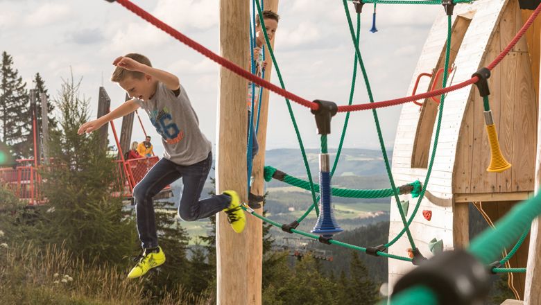Kinder spielen auf einem Klettergerüst im Freien.