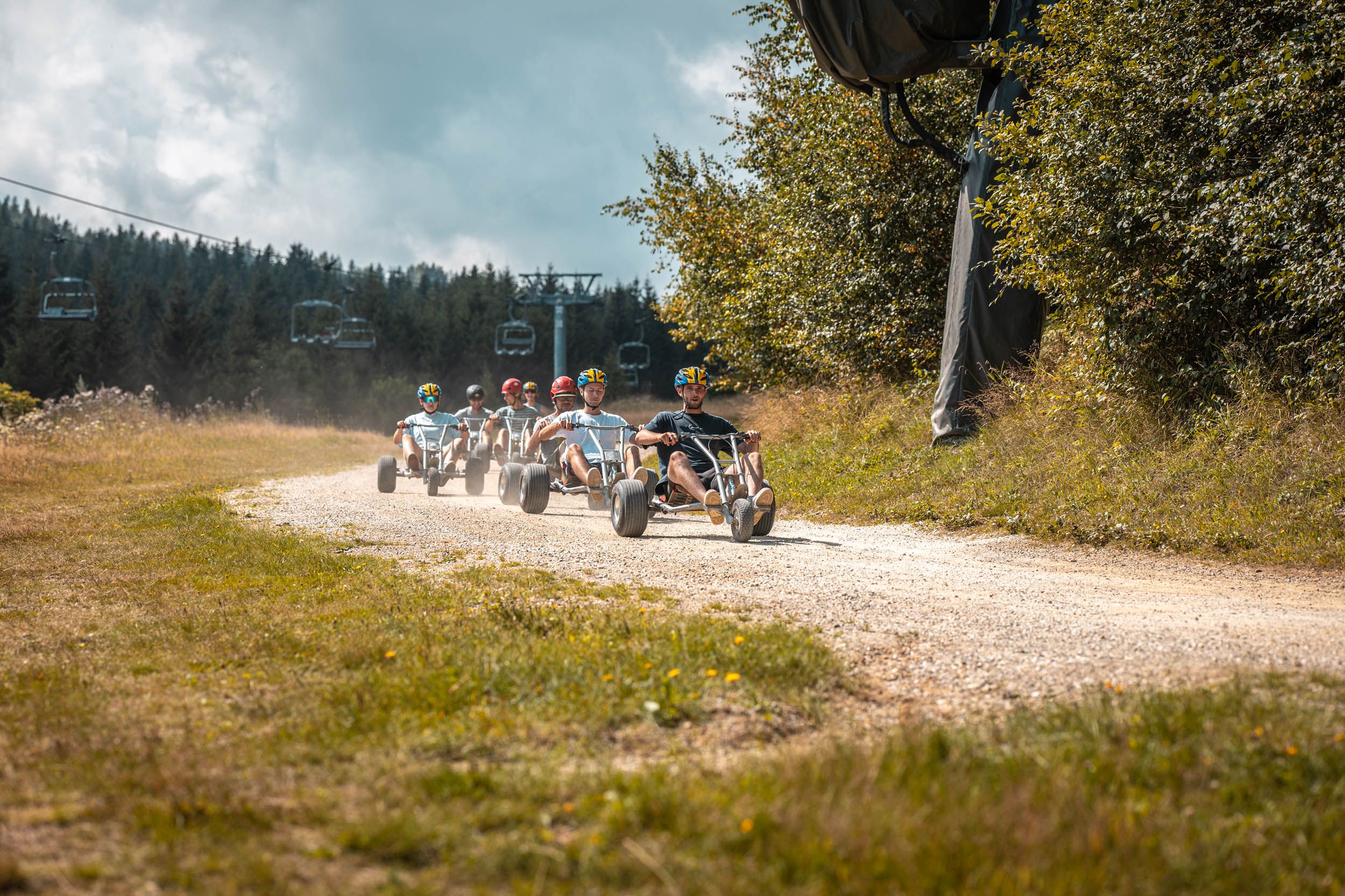 Mehrere Personen fahren gemeinsam mit Mountaincarts auf der Mountaincartstrecke. Die Gruppe ist auf der Strecke unterwegs und genießt die Fahrt durch die Natur.