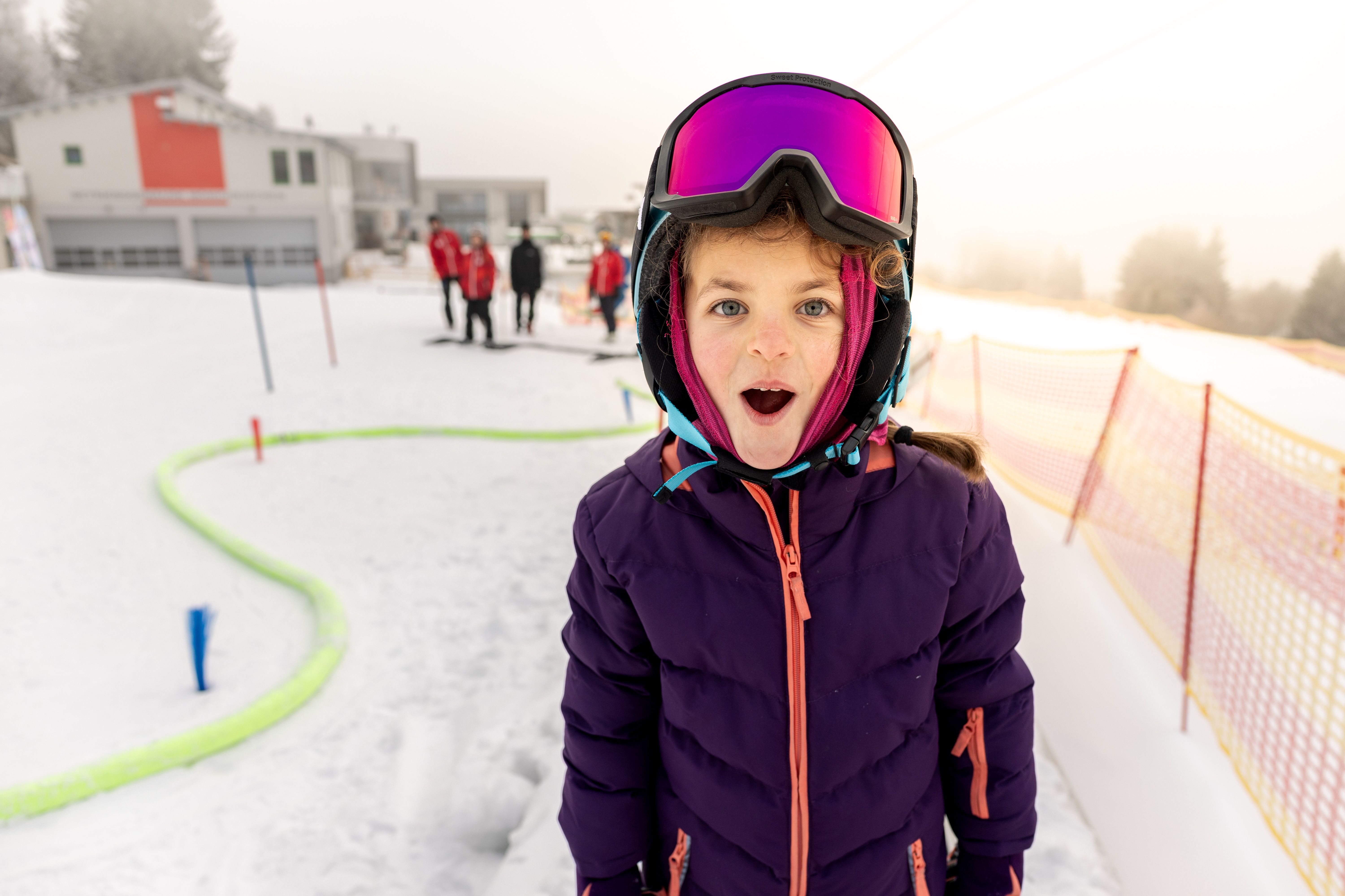 Mädchen beim Skifahren im Kinderland blickt überrascht in die Kamera.