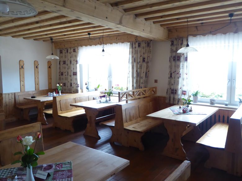 Gemütliches Gastzimmer mit Holzmöbeln und Blumen auf den Tischen.
