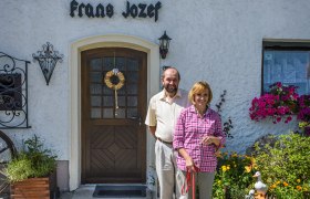 Egy h&aacute;zasp&aacute;r &aacute;ll a j&aacute;rd&aacute;n a Frans Jozef vend&eacute;gh&aacute;z előtt egy kuty&aacute;val.