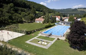 Freibad Edlitz mit Schwimmbecken, Rutsche und Volleyballfeld in l&auml;ndlicher Umgebung.