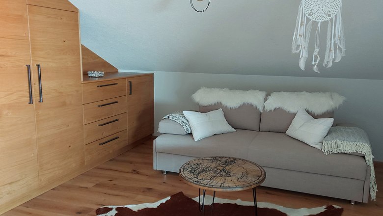 Cozy room with pull-out couch, wooden furniture and dream catcher.