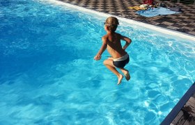 Ein Kind springt in einen Pool mit klarem, blauem Wasser.