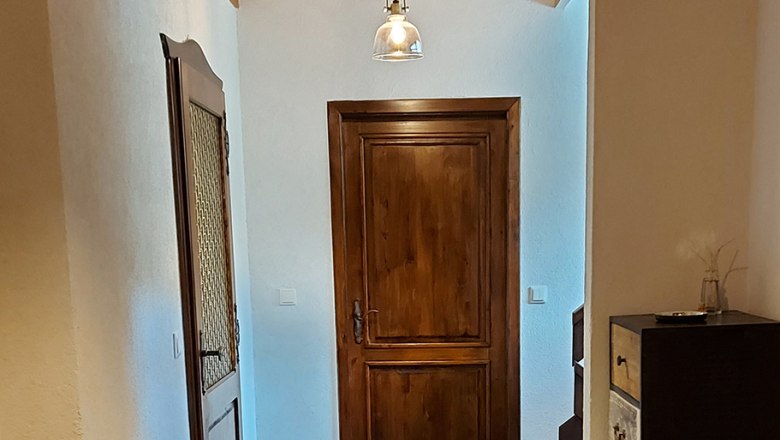 Egy előszoba fa ajt&oacute;kkal, fa mennyezettel &eacute;s modern l&aacute;mp&aacute;kkal.