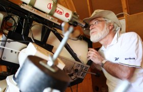 Ein Mann mit Hut schaut durch ein Teleskop in einer Sternwarte.