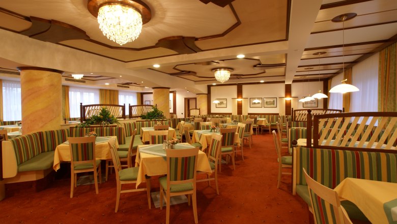 Eleganter Speisesaal mit Kronleuchtern und gestreiften Polstermöbeln.