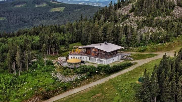 Culinary Stoa Alm, © Raphael Krapesch Aerial view of a mountain hut surrounded by forest and mountains.