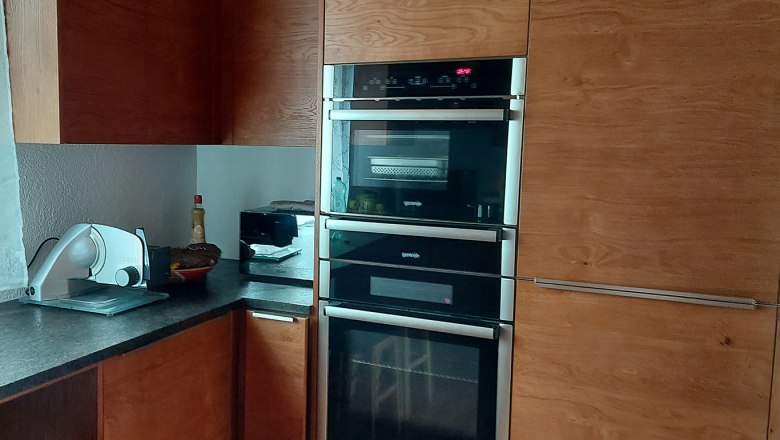 Modern kitchen with wooden cupboards, built-in oven and worktop with kitchen appliances.