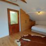 Bedroom with wooden floor, bed, wardrobe, door and TV.