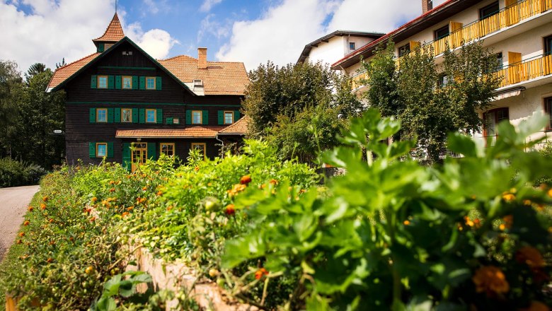 Seminar hotel NaturSinne, © Kloster NaturSinne A traditional building with green shutters and a garden in the foreground under a blue sky.