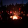People sit in a circle around a campfire at night.