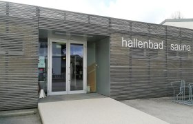 Eingang des Hallenbads mit Sauna in Scheiblingkirchen mit Holzvert&auml;felung und der Aufschrift "hallenbad sauna"