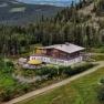 Aerial view of a mountain hut surrounded by forest and mountains.