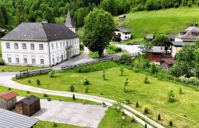 Landschaft mit historischem Geb&auml;ude, gr&uuml;nen Wiesen und B&auml;umen.