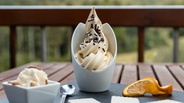 Desszert l&aacute;gy fagylalttal, csokol&aacute;d&eacute;sz&oacute;r&aacute;ssal, gofrival &eacute;s egy narancsszelettel az asztalon.